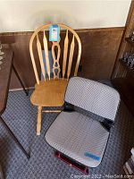 Two chairs side by side: one wooden chair with spindle back and one portable folding chair with fabric seat and back.