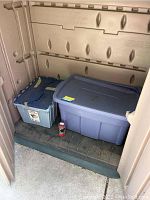 Two plastic bins on floor, one blue and one gray, containing Christmas light strings
