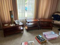 Wide shot of the coffee table flanked by two matching side tables in a room with curtains and carpet