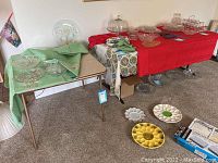 Two folding tables shown from distance among household items for scale and context.