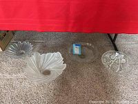 Four clear glass bowls with different decorative patterns displayed on carpet under table