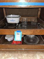 Shelf showing CorningWare casserole dish with Blue Cornflower pattern, two smaller square Pyrex glass bake dishes, Egglettes in plastic and pie plates below