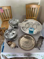 Full view of all serving pieces arranged on a table including trays, serving dishes, gravy boat, and decorative basket holder.