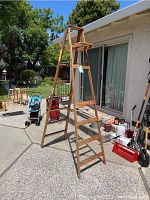 Full view of the Keller wood ladder standing open on a patio showing its five steps per side and top platform.