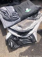 Three folded gray and black air mattresses stacked outside, showing wear