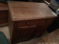 Front view of the vintage wooden cabinet showing the top, drawer, and door with wooden knobs.