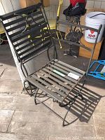 Two folding metal garden chairs with slatted seats and scrollwork back, outdoor setting on wooden floor.