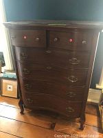 Front view of the wooden dresser showing six drawers with brass hardware and visible dovetail joints.