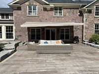 Extended awning above stone-faced house and patio furniture