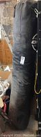 Full view of the heavy black punching bag showing its height and condition.