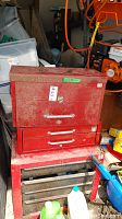 Front view of all three red toolboxes stacked, showing overall shape and surface rust