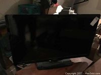 Large Philips flat-screen television with black frame and stand on floor.