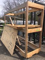 Side view of large wood framed shelf unit showing rectangular frame and plywood sheets laid on top.