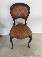 Front view of the Victorian-style armless chair showing upholstery and carved wooden frame details.
