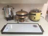 Photo showing the coffee urn, Rival crockpot, copper-colored fondue dish with stand and burner, and Rival electric hot tray on countertop.
