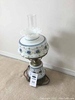 Front angle photo showing full lamp with blue floral pattern and brass fittings.