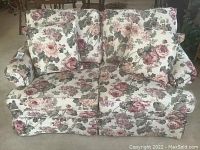 Floral fabric love seat front view showing cushions and floral pattern.