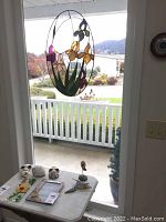 Photo showing stained glass panels on a table with outdoor background, includes floral and hummingbird designs