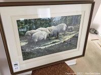 Framed watercolor print showing group of sheep grazing with trees in background, viewed showing overall artwork and frame