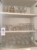 Multiple shelves with various clear glass wine and bar glasses of different types and sizes.