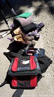 Photo showing hiking knapsack, men's boots, deck shoes, cooler bag, travel bag, sleeping bag, and camping towel arranged on floor.