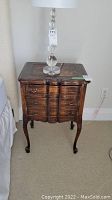Front view of one bedside table with glass ball lamp on top