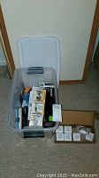 Plastic container with assorted boxed light bulbs including Philips and NOMA brands.