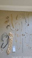 Photo showing various necklaces, bracelets, rings, and earrings laid out on carpet, including a chunky cream bracelet and pendant necklaces.
