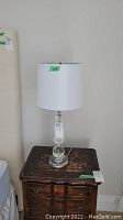 Plexi glass lamp with stacked ball base and white cylindrical shade on wood table