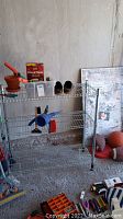 Metal rack holding garden items, including a terracotta pot, gardening shoes, and Blood Meal fertilizer box.