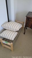 Shoe rack with two striped beige and white pillows placed on top of it