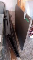 Side view of the folded rectangular table showing the folding legs and damaged condition.