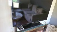 Front view of Samsung 41 inch TV on glass TV stand with two remote controls in front.