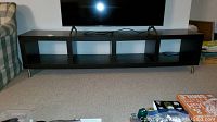 Full front view of wood veneer TV table with four cubbies and metal legs, displaying condition and size under TV.