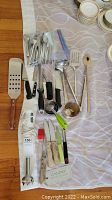 Overview of all kitchen utensils including flatware, knives, cooking utensils and part of the hand mixer