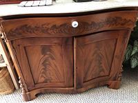 Front view of the wooden chest showing wood grain, marble-like top, and cabinet doors with one door misaligned.
