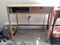 Front view of IKEA Nordkisa wooden desk showing single sliding drawer with a finger pull and worn surface.