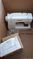 Janome Harmony 1017 sewing machine with manual and power cord inside a cardboard box.