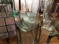 Photo shows four vases including two frosted glass ones with etched patterns and two clear glass vases with different shapes. Also includes a glass gadget barometer with measurement markings on the cup-shaped top and a pedestal base.