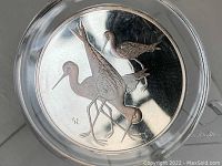 Front of the round silver medallion showing three Black-Necked Stilt birds in relief detail.