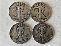 Obverse side of four Walking Liberty half dollar coins showing dates 1947, 1941, 1937, and 1940