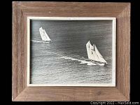 Framed photo of two sailing ships, showing the entire framed item from an overhead angle, highlighting frame texture.