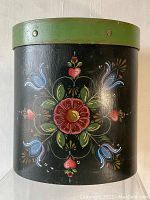 Front view showing colorful floral hand-painted design on black background with green rim