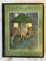 Front cover of the book showing illustration of Peter Pan sitting outside a cottage at night.