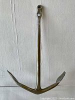 Full view of a small naval metal anchor showing its traditional shape and condition