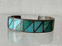 Front view of sterling silver cuff bracelet with turquoise triangular inlays.