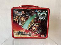 Front side of the lunchbox showing the Decepticon emblem and space battle scene.
