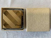 Photo of vintage compact in original textured beige box with fabric interior padding, top view