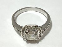 Close-up view of the Swarovski ring showing the square radiant cut center crystal and halo of smaller crystals on a silver rhodium plated band. The condition shows some missing small chatons.