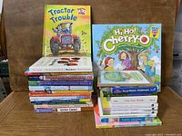 Stack of 24 children's books with Hi Ho! Cherry-O game box on top, showing various titles and condition
